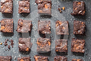 Chocolate brownie cake squares on black mottled texture background - top view angle