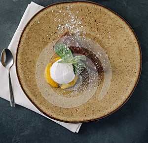 Chocolate brownie with ice cream and vanilla powder on plate