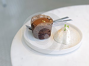 Chocolate brownie lava cake served with whip cream on white round plate