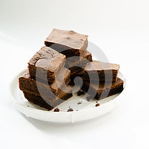 Chocolate brownie sliced into square slices on a white plate