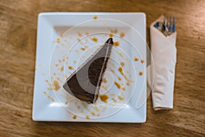 Chocolate brownie on the white plate and wooden table, top view