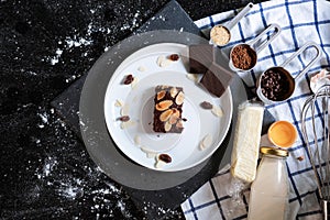 Chocolate brownies on white dish, surround with ingredients