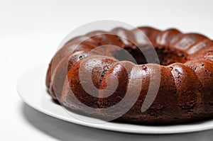 Chocolate bunt cake whole sponge on a plate white background closeup