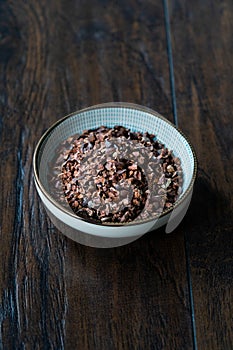 Chocolate Cacao Nibs or Cocoa Nibs in Bowl Ready to Use on Dark Wooden Surface