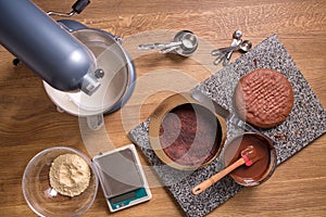 Chocolate cake baking ingredients on kitchen table with kitchenware, top view
