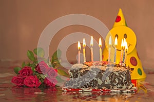 Chocolate cake with candles and red rose for valentines day, mothers day or birthday