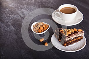 Chocolate cake with caramel, peanuts and almonds on a black wooden background