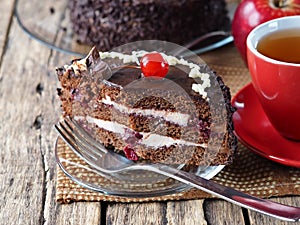 Chocolate cake with cherries or cherries on a wooden background with taped apples and a Cup of tea