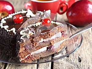 Chocolate cake with cherries or cherries on a wooden background with taped apples and a Cup of tea