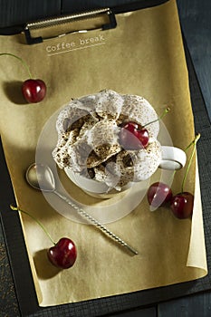 Chocolate cake with cherries and a cup of coffee with whipped cream. Coffee break.