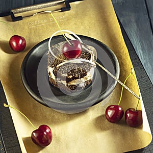 Chocolate cake with cherries and a cup of coffee with whipped cream. Coffee break.