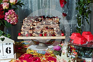 Chocolate cake with cherries on festive table. Candy bar and sweet cherry pastry for Birthday party or event.