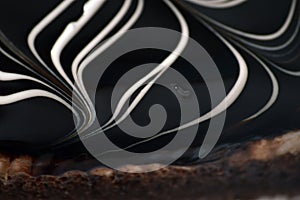 Chocolate cake close-up. White curved lines on a dark brown background. Striped chocolate pattern. Icing on the cake
