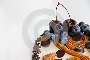 Chocolate cake with cream and blueberries with cherry on a white background photo