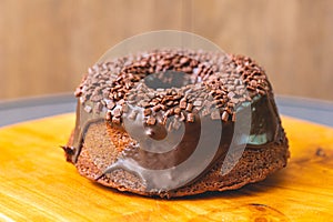 Chocolate cake with creamy chocolate sauce and decorated with chocolate sprinkles on a wooden board. photo