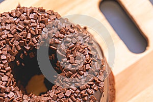 Chocolate cake with creamy chocolate sauce and decorated with chocolate sprinkles on a wooden board. photo
