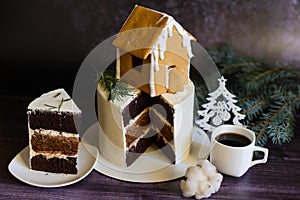 chocolate cake decorated with a gingerbread house, with a cut piece next to it