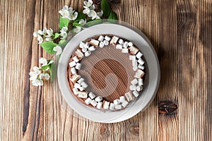 Chocolate cake, decorated with marshmallow, nougat, jasmine flowers on brown wooden table