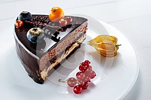 Chocolate cake with decoration and fruits on white wooden background