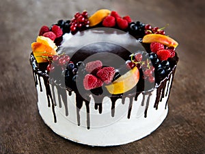 Chocolate cake with fruits on rustic wooden background