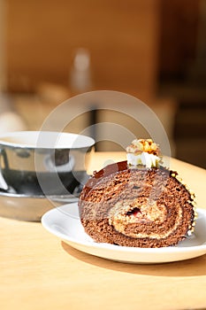 Chocolate cake with ground nuts on top. Sweet swiss chocolate roll and coffee in cafe