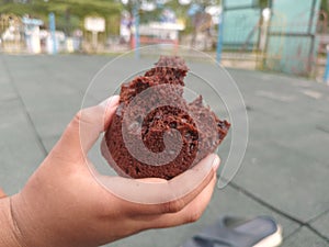 a chocolate cake that has been bitten in a boy& x27;s hand