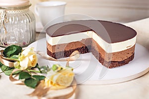 Chocolate cake made of three different chocolate mousse layers , white , milk and dark with chocolate