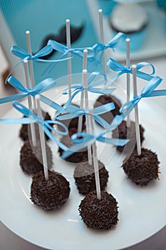 Chocolate cake pops on the plate with blue ribbons