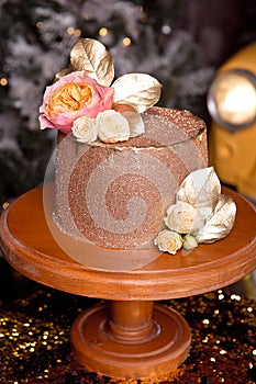 Chocolate cake with raspberry filling and pistachio cream, decorated with roses and golden jelly sparkles in the New