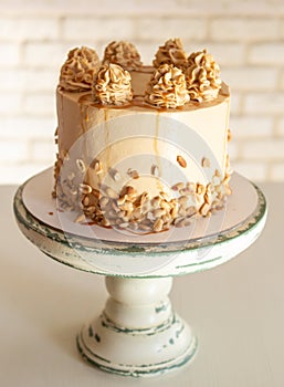 Chocolate cake with salted caramel, peanuts, decorated with chocolate, nuts and pieces of chocolate on a wooden