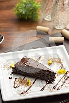 Chocolate cake with shinny chocolate ganache frosting on blurred background