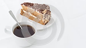 Chocolate cake slice with curl on white dish with hot drink