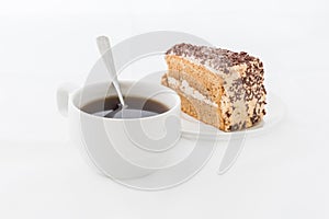 Chocolate cake slice with curl on white dish with hot drink