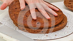 Chocolate cake sliced in into three layers. Step by step chocolate cake with chocolate cream frosting recipe, woman hands