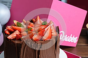 Chocolate cake with strawberries, basil leaves, blackberry jam and chocolate plates. Written in Portuguese: Congratulations.