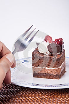 Chocolate cake with strawberry,fork and hand