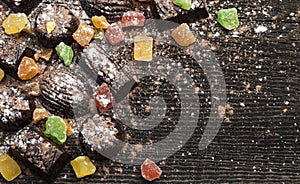 Chocolate candies, candied fruits on a wooden background