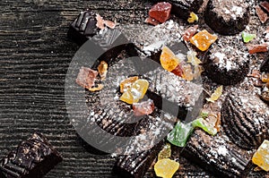 Chocolate candies, candied fruits on a wooden background