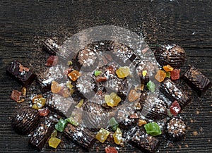 Chocolate candies, candied fruits on a wooden background