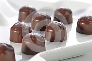 Chocolate candies with cherry filling without wrappers laid out on a white plate close-up. Dolce vita.