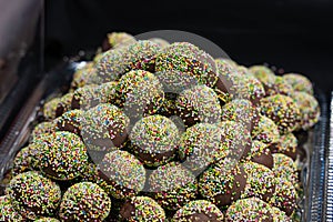 Chocolate candies in colorful sprinkles close-up, sweet dessert background