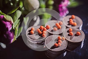 Chocolate candies with peonies on a dark mirror background