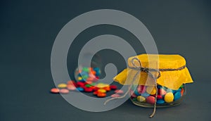 Chocolate candies, small multi-colored in a jar with a bow.