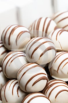 Chocolate candies with white fondant with a pattern of chocolate lines close-up