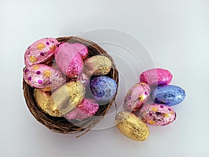 Chocolate candy easter eggs overflowing a twig birds nest on a white background