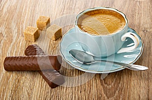 Chocolate candy, sugar, coffee in cup, spoon on saucer on table