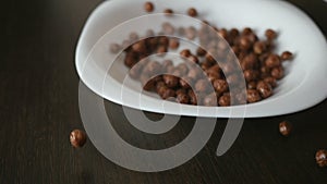 Chocolate cereal balls in white bowl for breakfast, close-up