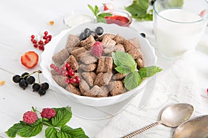 chocolate cereal pads with berries in bowl Healthy tasty breakfast chocolate square pads with strawberries, raspberries