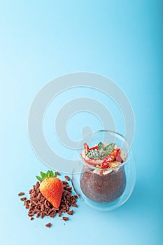 Chocolate Chia pudding decorated with strawberry on blue background
