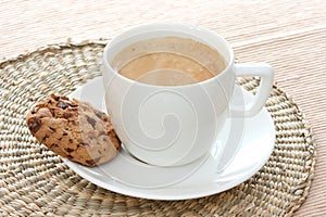 Chocolate chip cookie on saucer with coffee